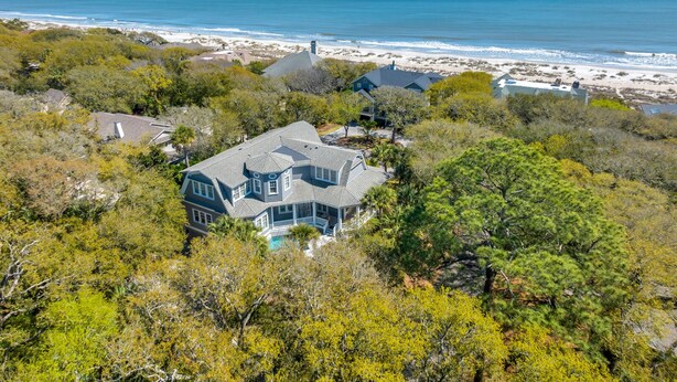 A large house with a spacious deck overlooking a beach and ocean.