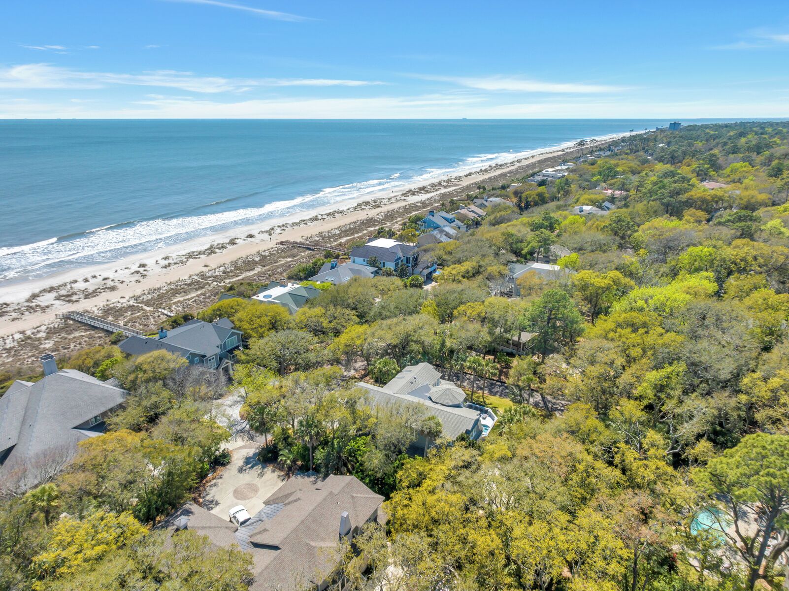 A coastal residential area with houses, a beach, and a clear sky.