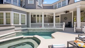 A pool area with a hot tub, lounge chairs, and a dining table with breakfast items.