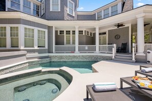 Un espace piscine comprenant un jacuzzi, des chaises longues et une table à manger avec des produits pour le petit-déjeuner.