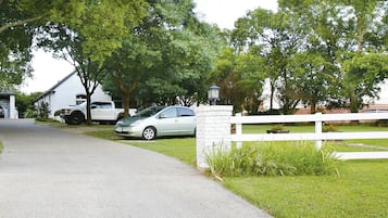 Une allée menant à une maison portant le numéro 450, avec une clôture blanche et une voiture garée.