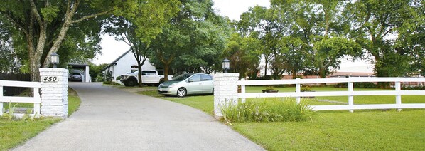 Un vialetto che conduce a una casa con un numero 450, un recinto bianco e un'auto parcheggiata.