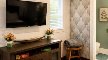 Un salon doté d’un téléviseur à écran plat, d’un meuble de rangement en bois, d’une horloge et d’un mur orné d’un motif.