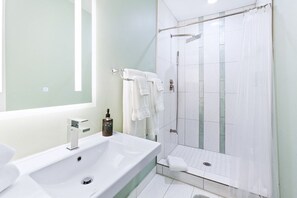 Un bagno moderno con un lavandino ampio, una cabina doccia in vetro e uno specchio con illuminazione a LED.