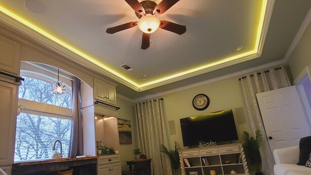 A bedroom with a bed, a ceiling fan, a TV, a desk, a chair, and a window with curtains. - Guest Efficiency at Gold Farm (McKinney)