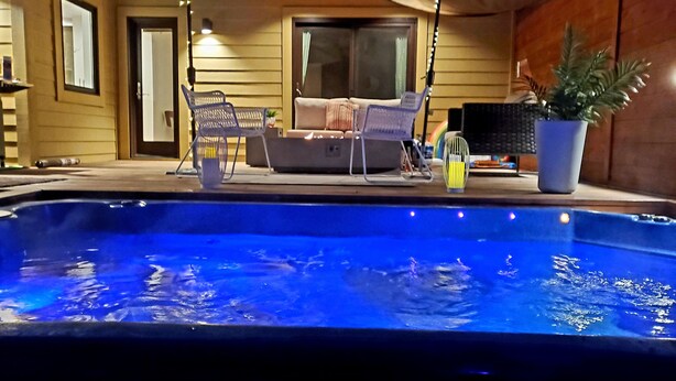 A swimming pool with lounge chairs and umbrellas, surrounded by wooden walls and a large window. - Stunning new home on creek, with spa pool, 5min walk to wineries & restaurants (Glen Ellen)
