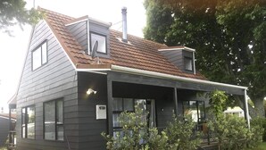 Een modern huis met twee verdiepingen, een schuin dak, grote ramen en een overdekte veranda.