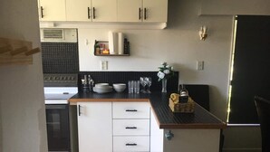 Een kleine keuken met witte kasten, een zwart aanrecht en een roestvrijstalen koelkast.