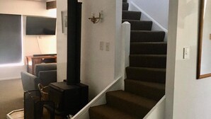 Een trap die leidt naar een tweede verdieping, met een ingebouwde open haard en een flatscreen televisie aan de muur.