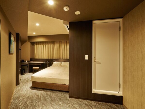 Una habitación de hotel con cama, escritorio y armario.