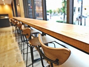 Una barra de madera larga con sillas de metal en un interior moderno.