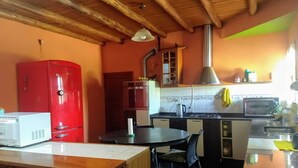 A compact kitchen with a red refrigerator, a microwave, a stove, and a sink. There is a dining table with chairs and a wooden ceiling. - House for rent for this summer 2021 in San Rafael Mendoza (San Rafael)