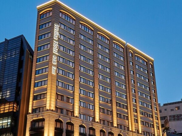 Un grand immeuble d’hôtel au design moderne, comprenant de nombreux étages et une entrée imposante.