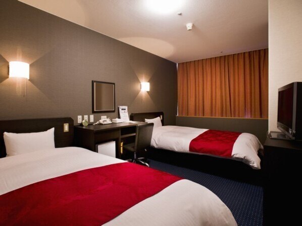 A hotel room with two beds, a desk, a chair, a television, and a window with curtains. - Standard Twin B  Smoking  Breakfast included pl / Kagoshima Kagoshima (Kagoshima)