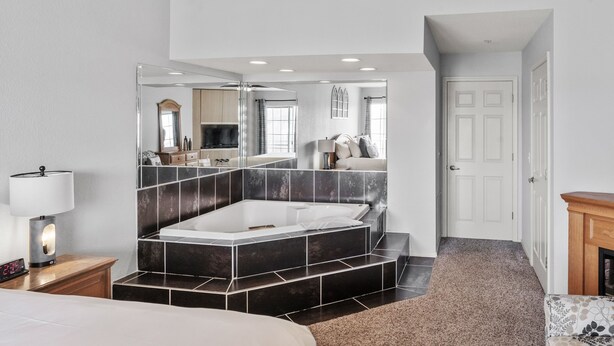 Ein modernes Badezimmer mit einer großen Badewanne, einem Spiegel und einer Uhr auf dem Nachttisch.
