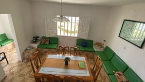 Ein Essbereich mit Holztisch, Stühlen und einem grünen Sofa.