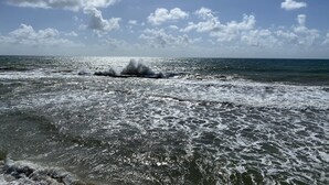 Ein Strand mit brechenden Wellen unter blauem Himmel.