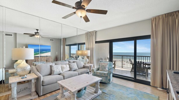 A spacious living room with a sofa, a coffee table, and a balcony with a view of the ocean. - The Palms 513 by Liquid Life (Orange Beach)