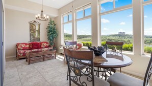 A spacious room with a dining area, a sofa, and a view of a landscape. - Luxury Walk-In Condo • 2 King Suites • Sunroom + Patio • Near Branson Fun! (Branson)