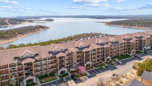 A multi-story apartment building with a parking lot and a view of a large lake. - Luxury Walk-In Condo • 2 King Suites • Sunroom + Patio • Near Branson Fun! (Branson)