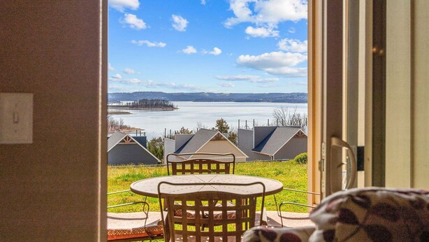A room with a view of a body of water, a dining table, and chairs. - Luxury Walk-In Condo • 2 King Suites • Sunroom + Patio • Near Branson Fun! (Branson)