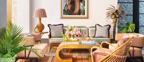 A well-lit living room with a sofa, chairs, a coffee table, and a large framed picture on the wall.