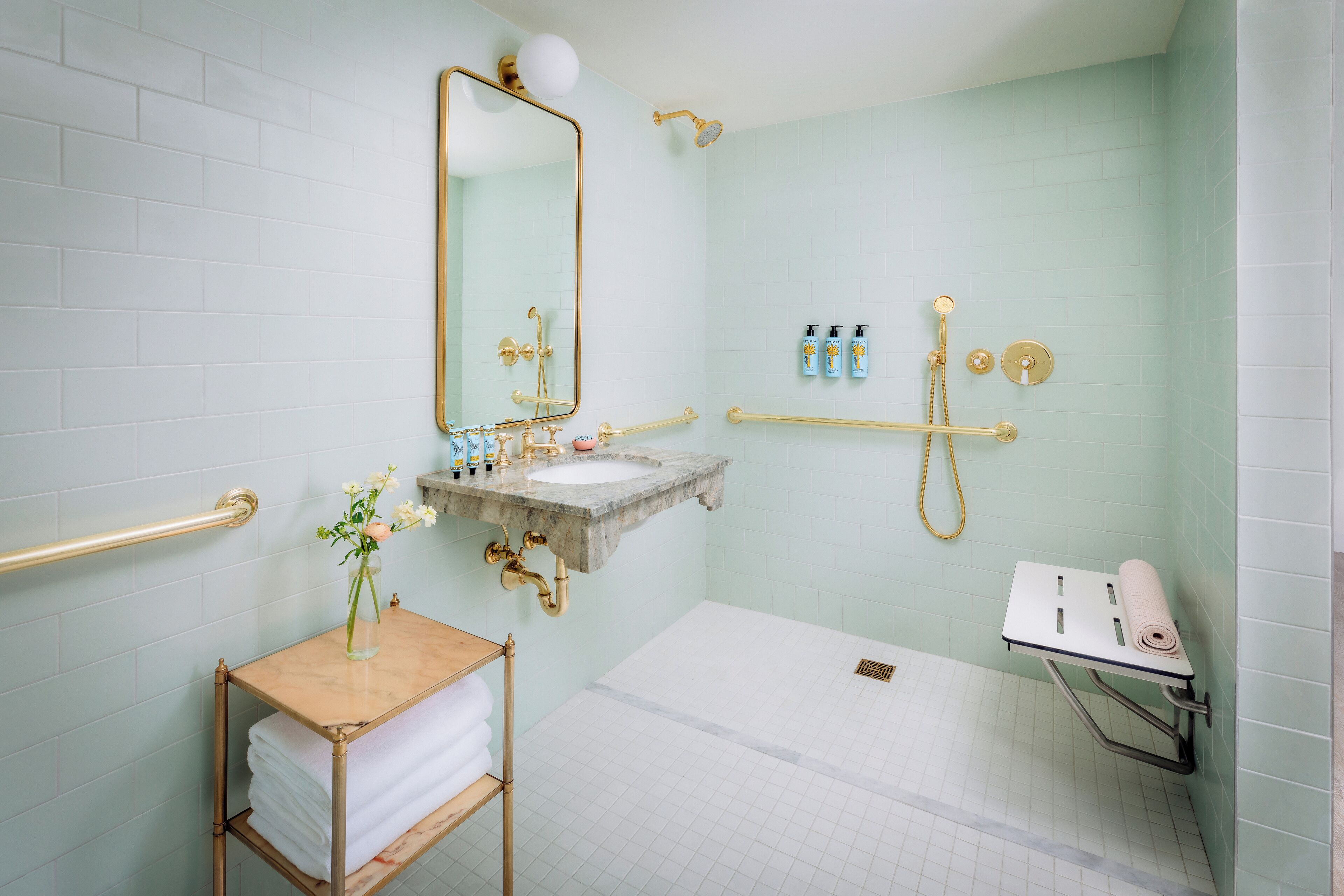 Une salle de bain avec un lavabo en marbre, un grand miroir, une douche et un porte-serviettes.