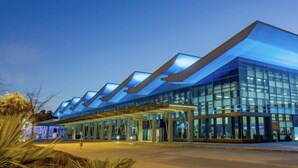 A modern building with a glass facade and a covered entrance area.