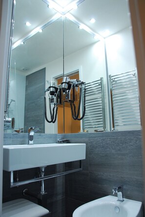 A modern bathroom with a large mirror, a sink, a toilet, and a towel rack. - Rapallo Suites (Rapallo)