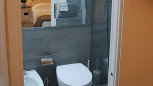 Ein modernes Badezimmer mit zwei Waschbecken, einer Toilette und einer Duschkabine aus Glas.