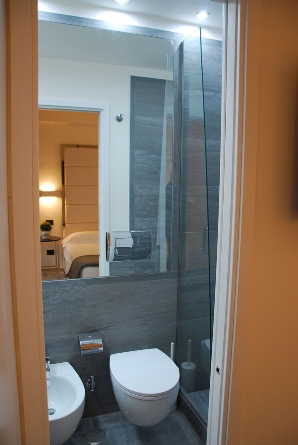 A modern bathroom with two sinks, a toilet, and a glass shower enclosure. - Rapallo Suites (Rapallo)