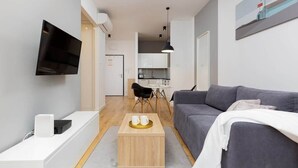 Ett modernt vardagsrum med en grå soffa, ett soffbord och en platt-TV som är monterad på väggen.
