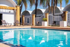 A swimming pool with lounge chairs and a covered area with arched ceilings. - Ibis Styles Rio Preto Monte Libano (São José do Rio Preto)