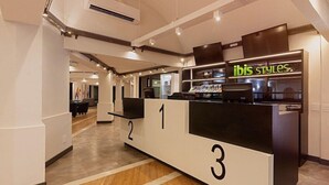 A modern hotel reception area with numbered counters and a visible 'ibis styles' sign. - Ibis Styles Rio Preto Monte Libano (São José do Rio Preto)