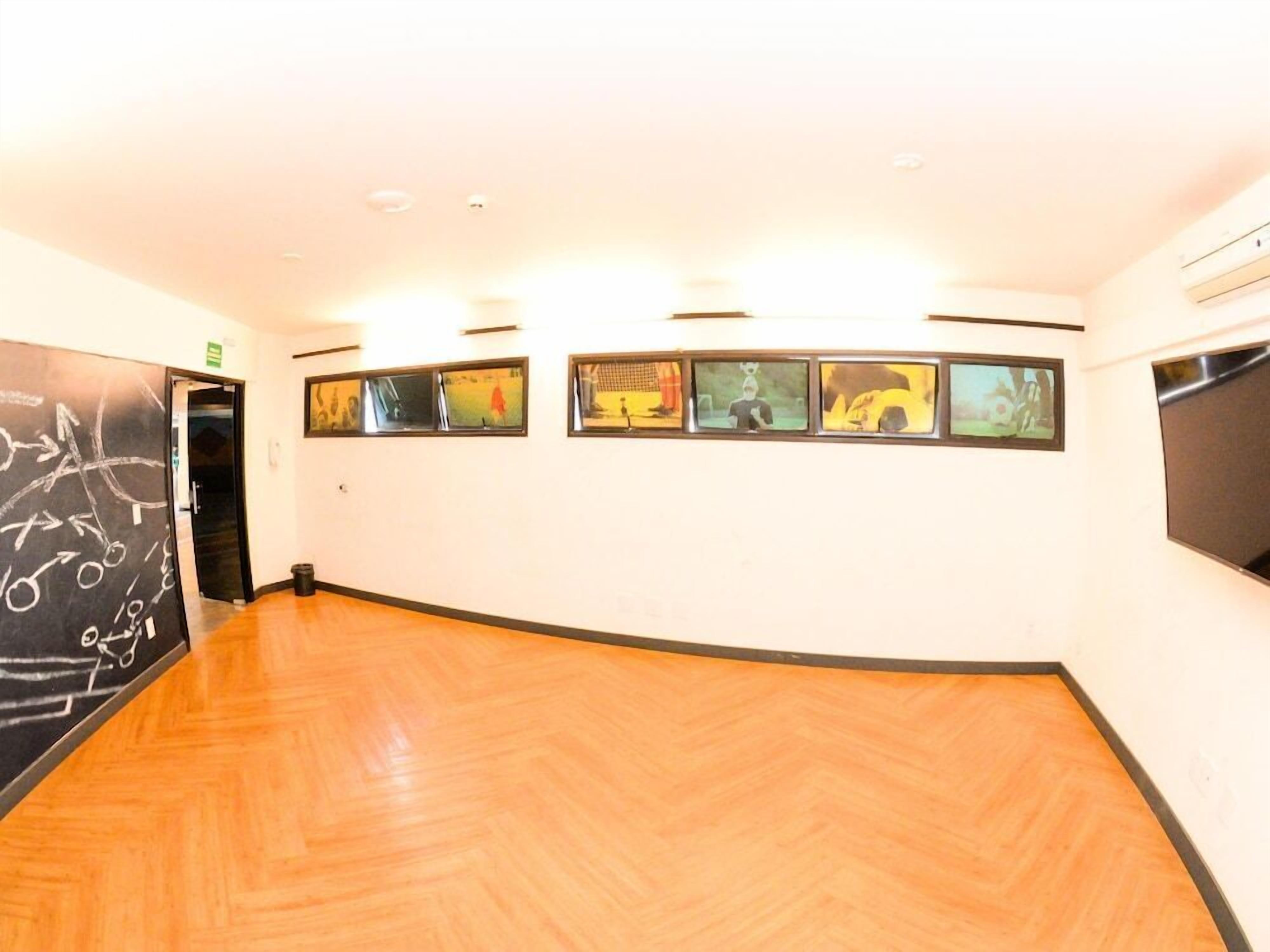 A room with wooden flooring, a blackboard with chalk drawings, and a series of framed pictures on the wall.