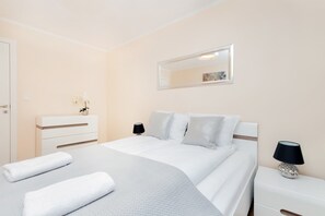 Une chambre à coucher moderne avec un grand lit, des tables de chevet, une commode et un miroir au mur.
