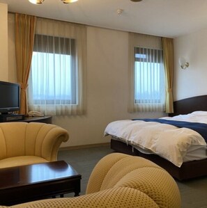 Relax in this serene space with a single bed, sofa, and television, surrounded by sheer curtains and carpeted floors.