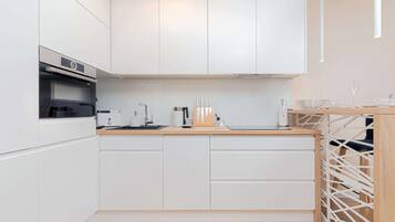 A modern kitchen with white cabinetry, a built-in oven, and a wooden countertop.