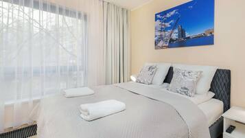 A hotel room with a large bed, two pillows, a nightstand, and a painting on the wall.