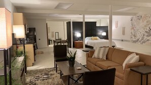 Una habitación de hotel moderna con sala de estar, una mesa de comedor, un sofá y una cama.