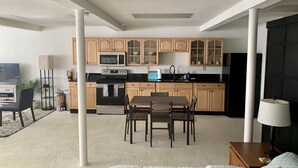 Un espacio habitable compacto con kitchenette, comedor y cama.