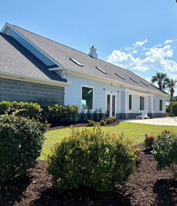 A modern building with a sloped roof, large windows, and a well-maintained garden with bushes and a lawn. - Little cottage near the sea!  Golf CART is included! (Garden City)