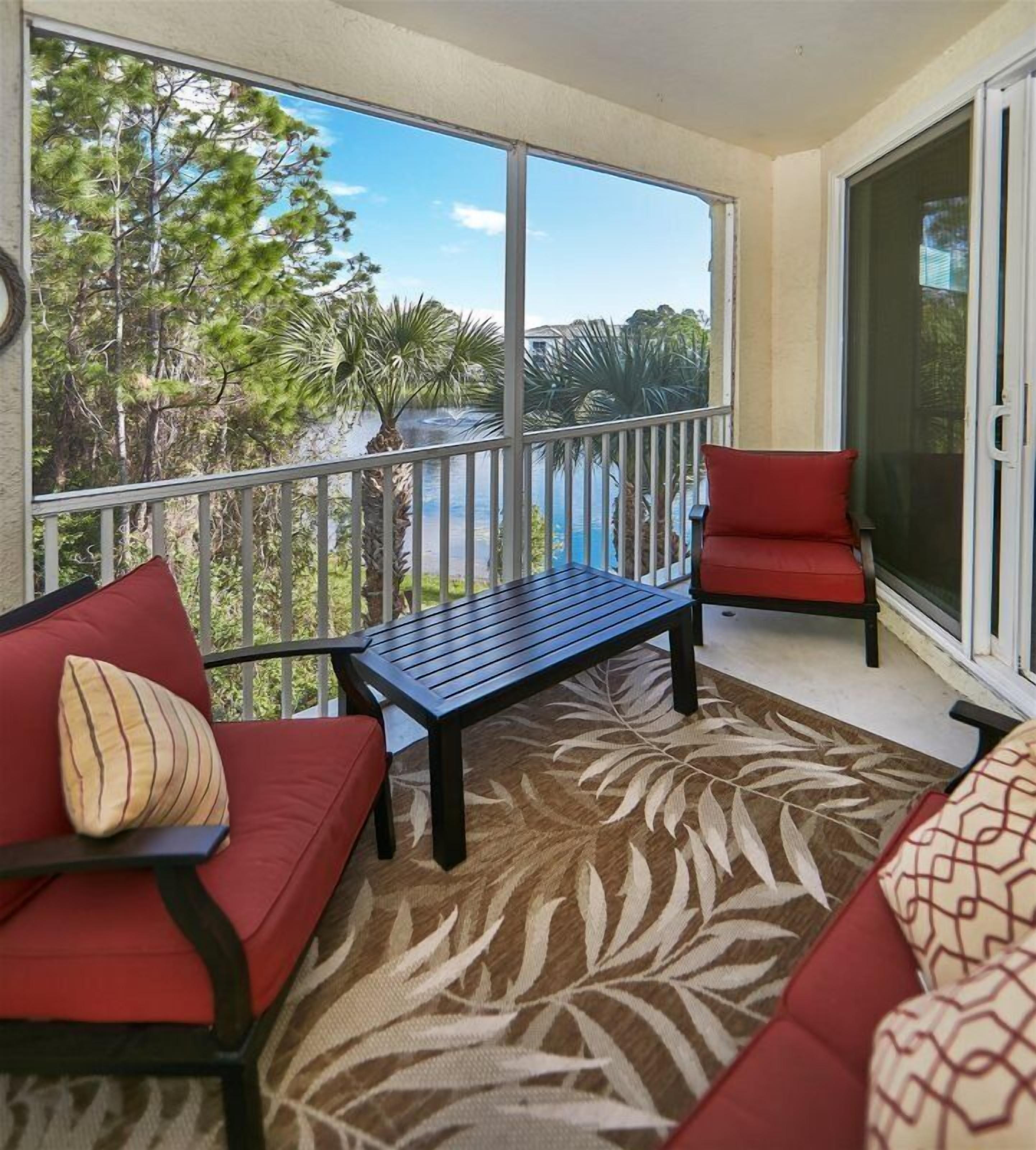 A balcony with a red sofa, a bench, and a red chair.
