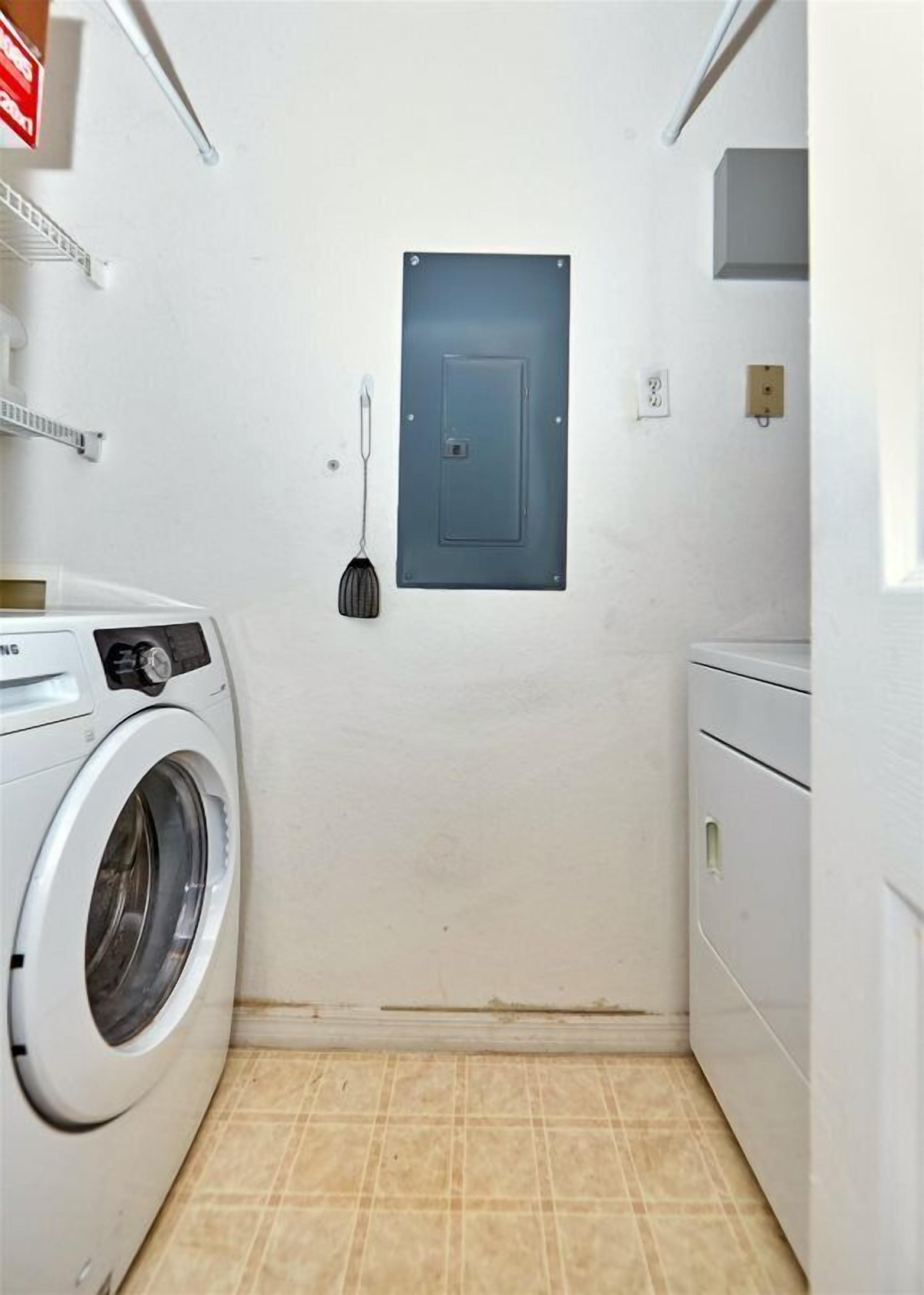 A laundry room with a washing machine, dryer, and a door with a light switch.