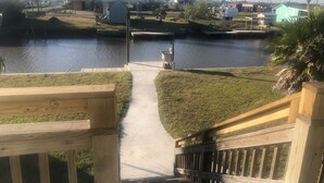 A wooden deck leading to a waterway with houses in the background. - Getaway By The Bay Unit 1 (Sargent)