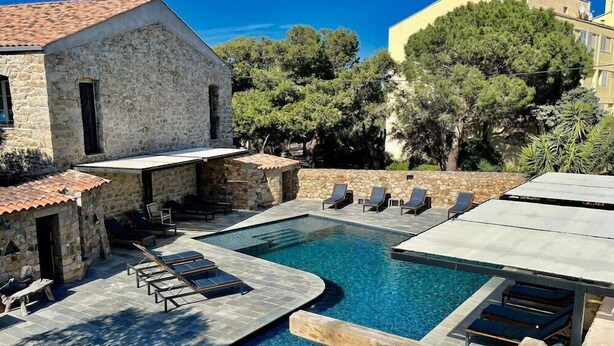 A pool area with lounge chairs and a stone building. - Hotel Casa Rossa (L'Île-Rousse)