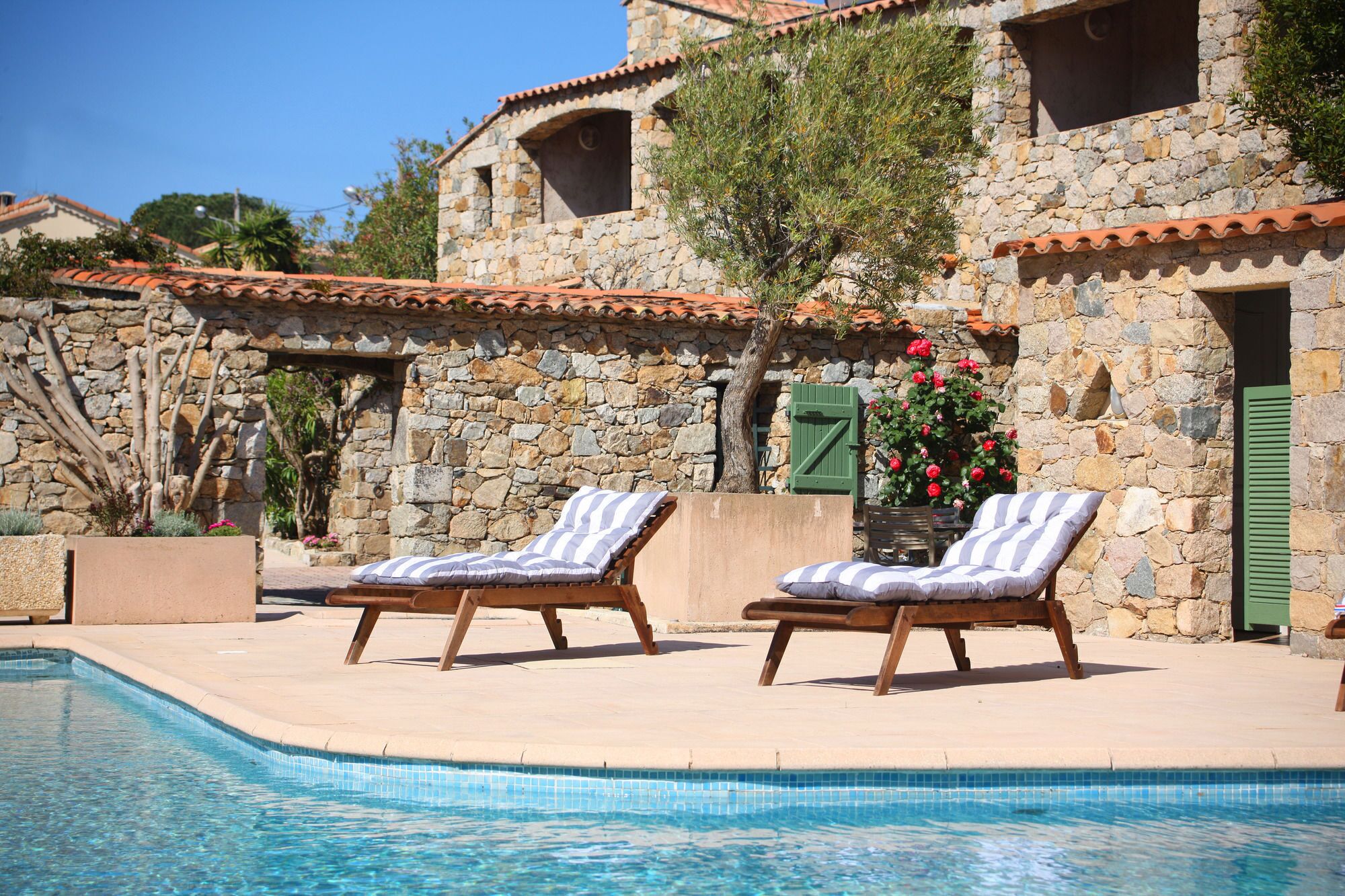A poolside area with two lounge chairs and a stone building in the background.