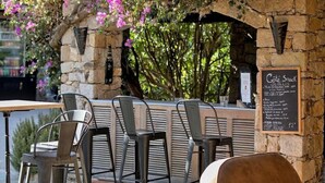 An outdoor café with stone walls, metal chairs, and a menu board. - Hotel Casa Rossa (L'Île-Rousse)