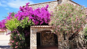 A stone building with a tiled roof, a reception area, and vibrant purple bougainvillea flowers. - Hotel Casa Rossa (L'Île-Rousse)