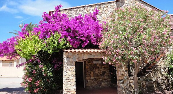 Een gebouw van steen met een betegeld dak, een receptie en levendige paarse bougainvillea bloemen.